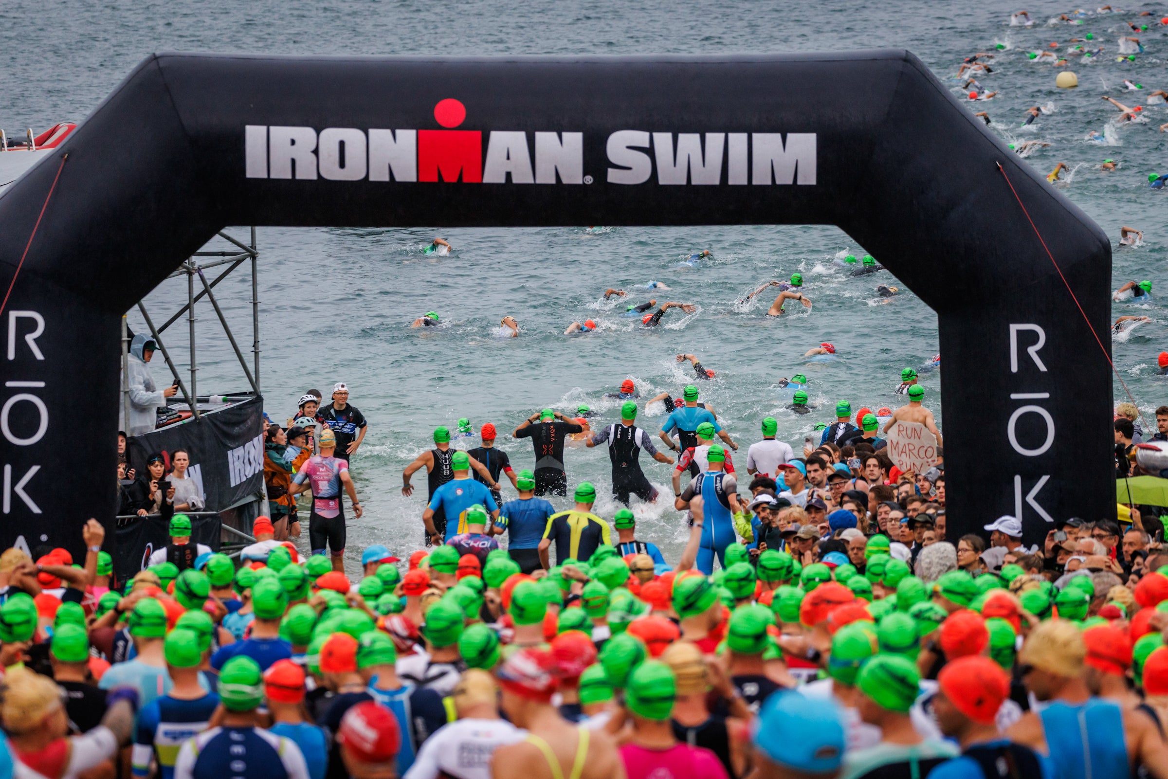 Schwimmstart beim IRONMAN Frankfurt. Athleten laufen im Rolling-Start-Verfahren durch den Startbogen ins Wasser