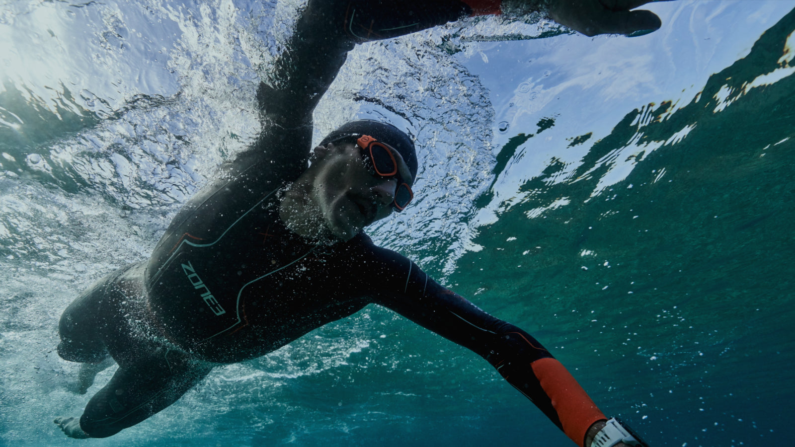 Unterwasseraufnahme eines männlichen Schwimmers mit Neoprenanzug beim Kraulschwimmen 
